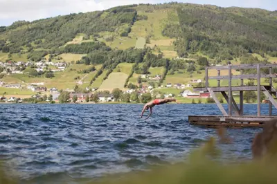 a man jumping into the water from a dock at Lyngmo Gjestehus in Hafslo