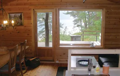 a log cabin with a large window and a table at Roligheten in Vanvik