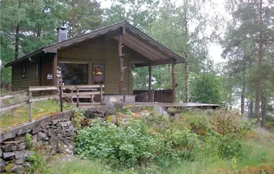 a small cabin in the woods with a porch at Roligheten in Vanvik