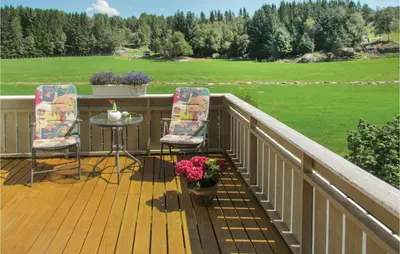 a deck with two chairs and a table and a field at 3 Bedroom Awesome Home In Skjold in Skjold
