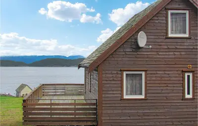 a wooden house with a large deck next to a lake at Holiday Home Bjoa Haugsgjerdet in Utbjoa