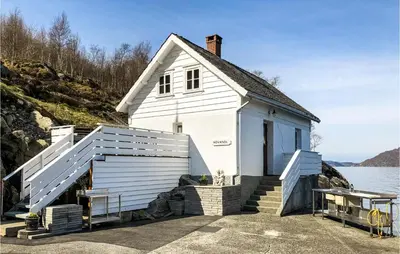 a small white building with stairs next to a body of water at Kyrping Ferieplass A in Erve