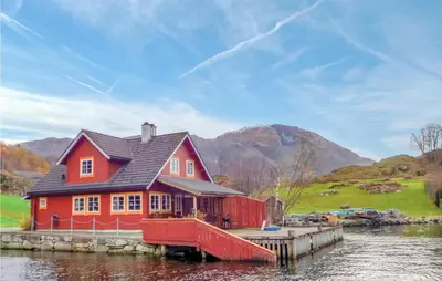 a red house on a dock on a body of water at Gorgeous Home In Åkra With Wifi in Åkra