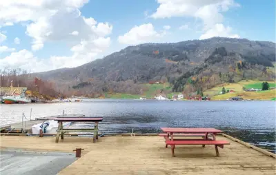 two picnic tables on a dock next to a lake at Gorgeous Home In Åkra With Wifi in Åkra