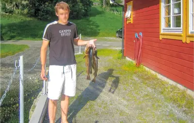 a young man holding a fish in his hand at Gorgeous Home In Åkra With Wifi in Åkra