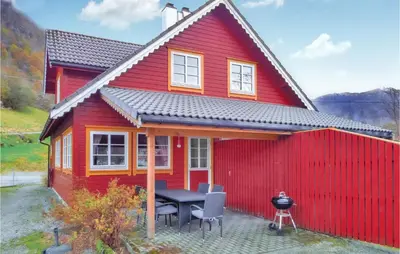 a red house with a table and chairs in front of it at Gorgeous Home In Åkra With Wifi in Åkra