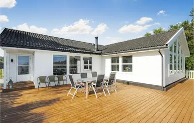 a white house with a deck with chairs and a table at 4 Bedroom Cozy Home In Auklandshamn in Vestvik