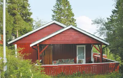 a red cabin with a porch in the woods at Stunning Home In Sandvoll in Sandvoll