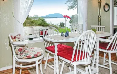 a dining room with a table and chairs and a window at Nice Home In Etne With House Sea View in Erve