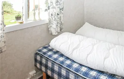 an unmade bed with a pillow and a window at Nice Home In Etne With House Sea View in Erve