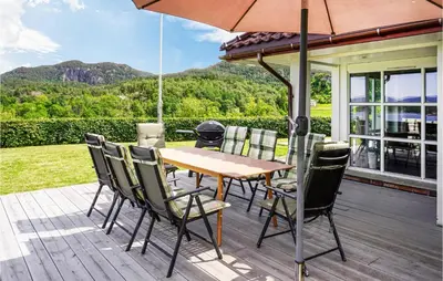 a wooden table and chairs with an umbrella on a deck at Nice Home In Lundegrend With Wifi in Grimsland