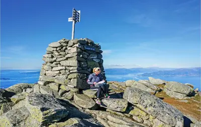 a woman sitting on top of a rock tower on a mountain at Nice Home In Lundegrend With Wifi in Grimsland