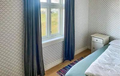 a bedroom with a bed and a window with blue curtains at Holiday Home Finnås Lykling in Vinnes