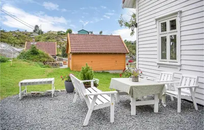 a patio with a table and chairs and a house at Holiday Home Finnås Lykling in Vinnes