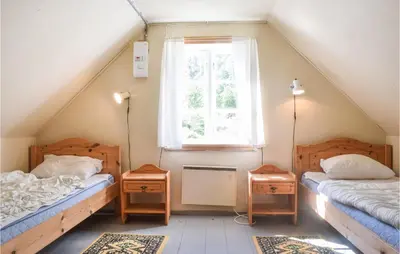 a attic room with two beds and a window at Holiday Home Nordtveitgrend Nedrevågen in Hjartåker