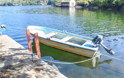 a small boat tied to a dock on a lake at Holiday Home Nordtveitgrend Nedrevågen in Hjartåker
