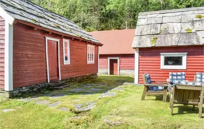 a red house with a table and chairs next to it at Holiday Home Nordtveitgrend Nedrevågen in Hjartåker