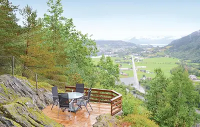 a deck with a table and chairs on top of a mountain at Cozy Home In Norheimsund in Norheimsund