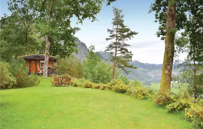 a cabin in the middle of a field with a grassy yard at Cozy Home In Norheimsund in Norheimsund