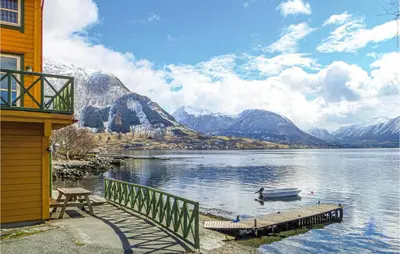 a man in a boat on a lake with mountains at Cozy Apartment In Rosendal in Rosendal