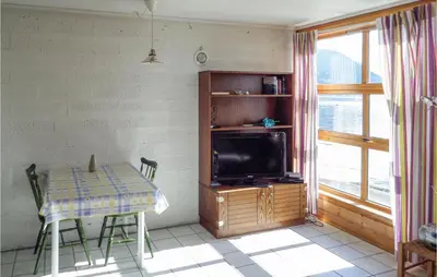 a dining room with a table and a television at Cozy Apartment In Rosendal in Rosendal
