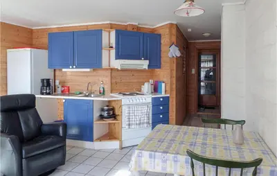 a kitchen with blue cabinets and a table and a chair at Cozy Apartment In Rosendal in Rosendal