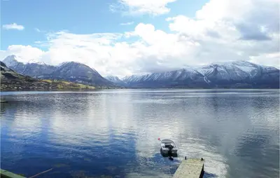 a boat in the middle of a lake with mountains at Nice Apartment In Rosendal With Sauna in Rosendal