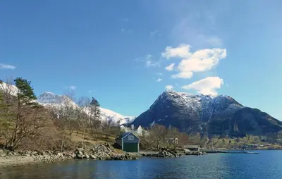 a house on the shore of a lake with a mountain at Cozy Apartment In Rosendal With Sauna in Rosendal
