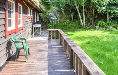 a green chair sitting on a wooden walkway next to a house at Eikhaugen Gjestegard in Husa