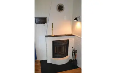 a fireplace in a living room with a clock on the wall at Cozy Apartment In Norheimsund With Wifi in Norheimsund