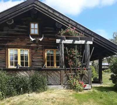 a log cabin with flowers in front of it at Fredelig plass for rekreasjon in Krøderen