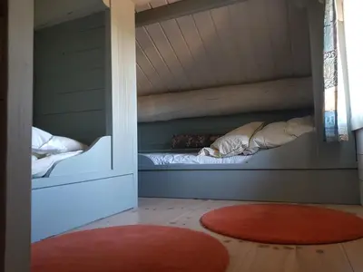 a bed in a room with a window and a red rug at Fredelig plass for rekreasjon in Krøderen
