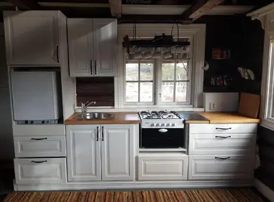 a kitchen with white cabinets and a stove and a sink at Fredelig plass for rekreasjon in Krøderen