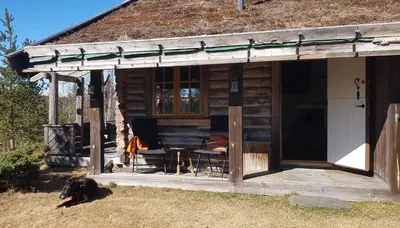 a log cabin with a table and chairs in front of it at Fredelig plass for rekreasjon in Krøderen
