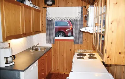 a kitchen with a stove and a van in the window at Beautiful Home In Nordtveitgrend in Haugen