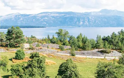 a view of a field with a lake and mountains at Nice Home In Hatlestrand in Hatlestrand