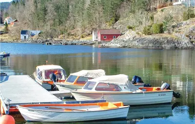 three boats are docked at a dock in the water at Beautiful Home In Hatlestrand in Hatlestrand
