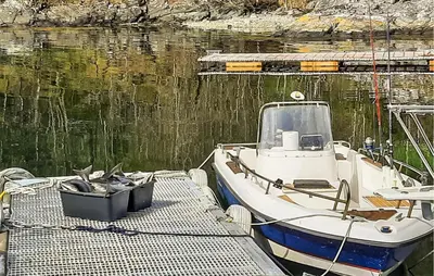a boat tied up to a dock in the water at Beautiful Home In Hatlestrand in Hatlestrand