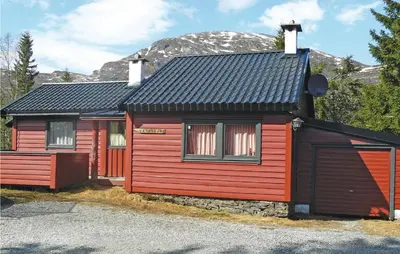 a red and black house with a mountain in the background at Petterbua in Norheimsund