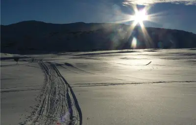 a sun is shining over a snow covered field at Petterbua in Norheimsund