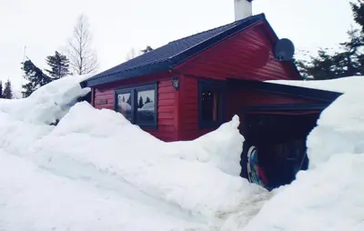 a red cabin with a pile of snow around it at Petterbua in Norheimsund