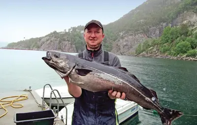 a man holding a large fish in front of a boat at Holiday Home Jondal Torsnes in Jondal