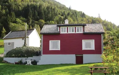 a red and white house in front of a mountain at Holiday Home Jondal Torsnes in Jondal