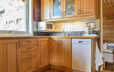 a kitchen with wooden cabinets and a white dishwasher at Stunning Home In Os With Kitchen in Oma