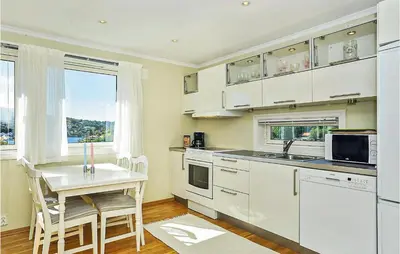 a kitchen with white cabinets and a table and a window at Cozy Apartment In Straumsgrend in Bergen