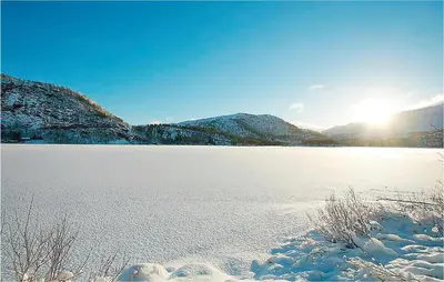 a snow covered lake with the sun in the background at Holiday Home Tysse Eikedal in Tysse