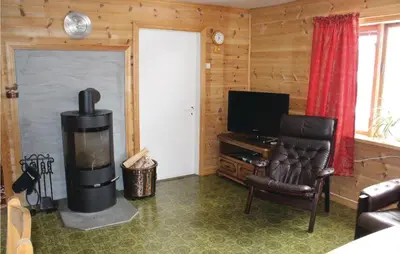 a living room with a fireplace and a chair and a television at Holiday Home Evanger Brekkhuslii in Evanger