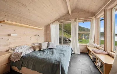 a bedroom with a bed in a room with windows at Sørkvingo in Masfjorden