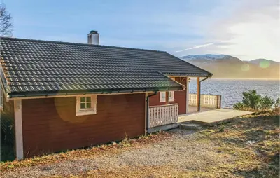 a small house with a deck next to the water at Cozy Home In Lavik With House Sea View in Lavik