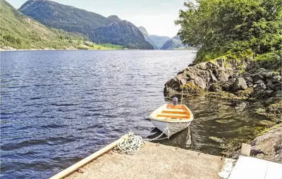 a small boat tied to a dock on a lake at Gorgeous Home In Dalsøyra With Kitchen in Dalsøyra